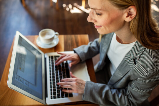 Smiling businesswoman typing on laptop in cafe