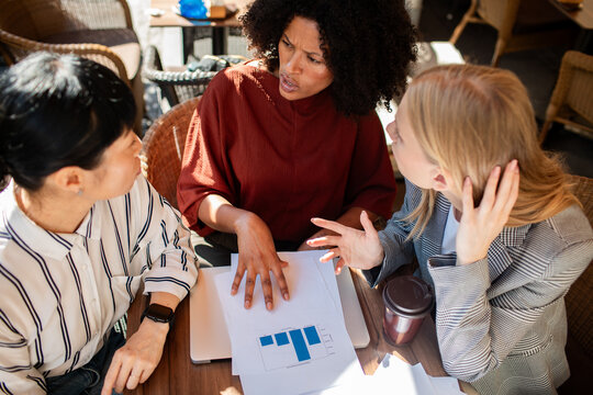 Three coworkers discussing bar chart at a cafe