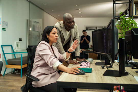 Woman explaining work to colleague at computer in office