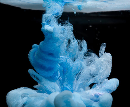 Bright blue ink swirling in water creating shapes and patterns