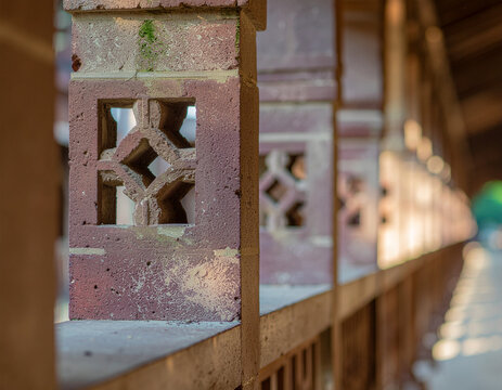 close-up perspective of decorative perforated sandstone pillars along a covered gallery walkway with warm sunlight casting rhythmic shadows