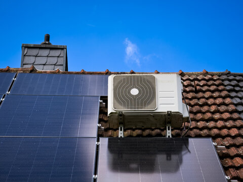 Eine Klimaanlage auf einem Dach eines Einfamilienhaus neben mehreren Solarpanelen in Essen, Deutschland