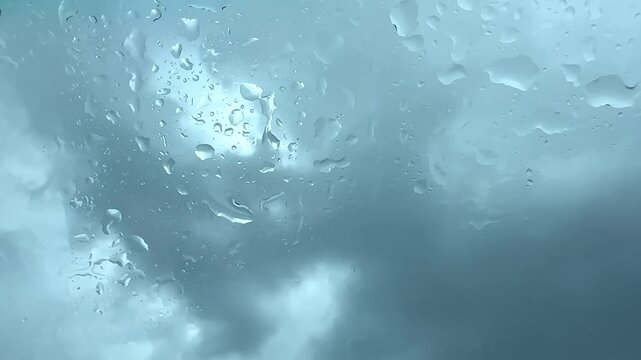 Raindrops on the windowpane and the overcast sky beyond.