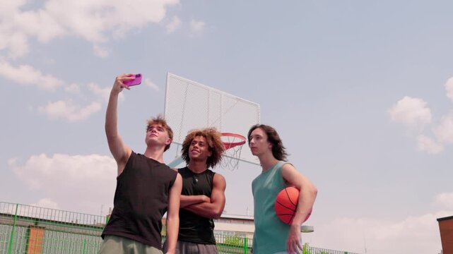 Multicultural male friends taking a selfie on an outdoor basketball court