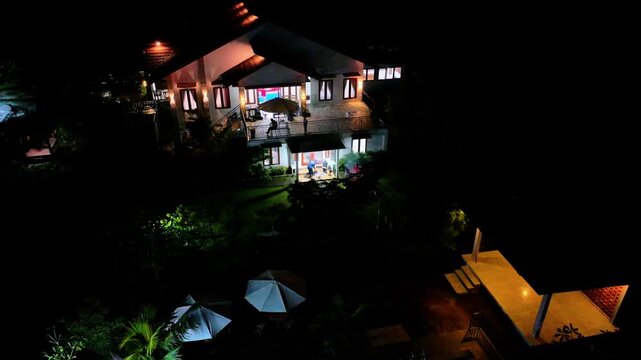 Aerial drone view of modern residential house illuminated with warm lights at night