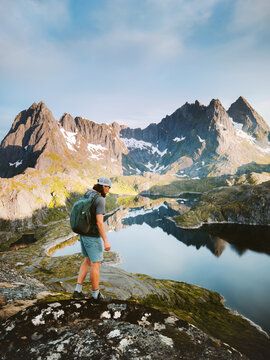 Man tourist backpacking in Lofoten islands hiking travel alone in Norway, active healthy lifestyle summer vacations adventure extreme tour outdoor traveler enjoying mountains and lake reflection view