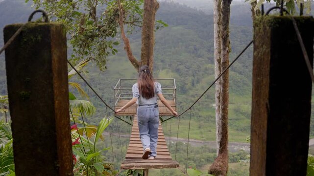 Mujer cruzando un puente colgante con la selva de la amazonia Ecuatoriana de fondo