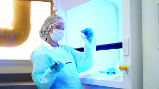 Scientist in protective gear performing precise chemical analysis inside a laboratory fume hood
