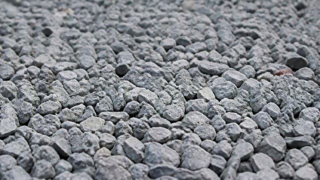 Gray crushed stone texture on gravel driveway. Close-up of coarse aggregate pebbles for landscaping and construction background