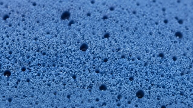 Blue foam rubber texture with porous cellular structure. Macro view of synthetic sponge gym mat surface background