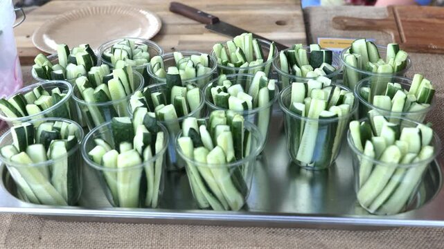 Cucumber sticks in plastic cups on a tray, a healthy market snack