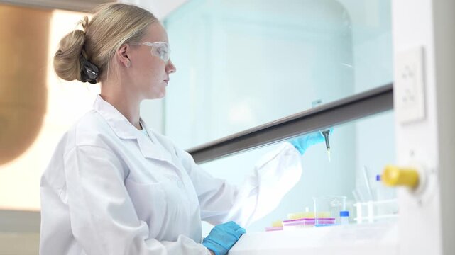 Scientist in a laboratory performing precise chemical analysis using a pipette and glass tubes