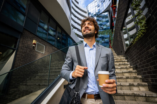 Low angle close up of businessman walking down stairs with coffee and bag