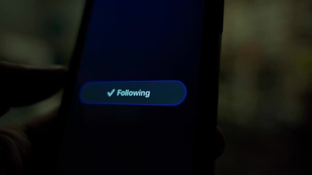 Finger tapping follow button on smartphone screen and switching to following state close-up