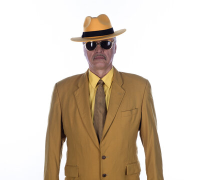 Portrait of a cheerful old man in yellow clothing and a yellow hat, isolated on a white studio background.