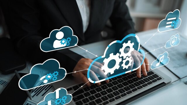 Business professional using laptop with cloud computing graphics showing data management and technology icons in a modern office environment. Entropy.