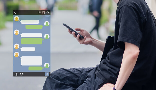 屋外でスマートフォンのメッセージアプリを使う若い男性　SNSのイメージ