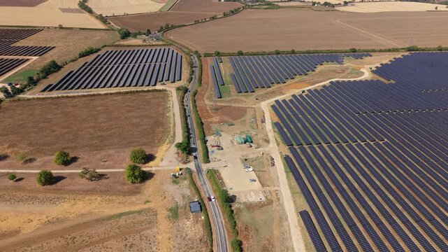 Aerial view of expansive photovoltaic solar farm array with an access road cutting through the middle near Eaton Socon, UK