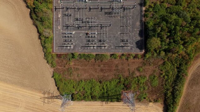 Top down aerial view of an electrical transmission substation connecting to high voltage pylon lines in Eaton Socon, UK