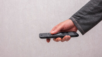 Hand holding a black television remote control. This image is perfect for technology, entertainment, home leisure, and lifestyle media projects. © ismailgazel