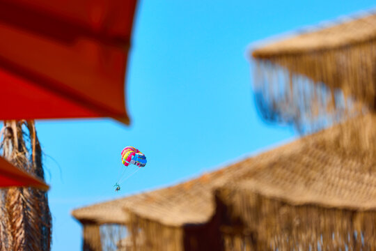 Colorful parasail flying above a tropical beach resort