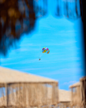 Colorful parasail flying above a beach resort with blue sky