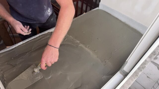 Worker leveling fresh cement mortar on a windowsill during home renovation, skilled craftsmanship, home improvement