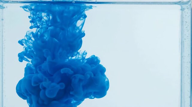 Vibrant blue ink swirling and expanding in clear water. Macro shot of fluid dynamics and abstract cloud patterns. Creative design element
