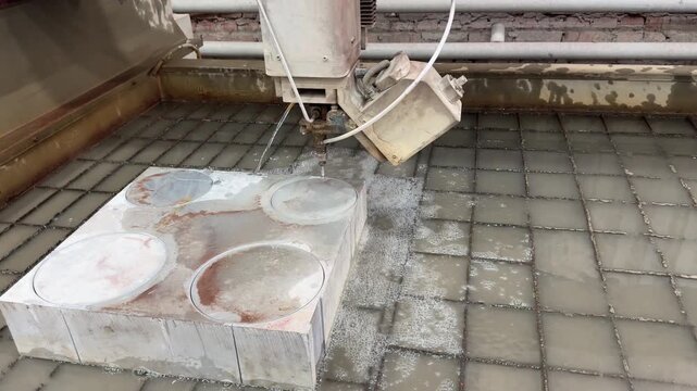 Waterjet cutting machine slices metal with high-pressure abrasive stream, producing precise edges amid water spray in an industrial workshop.