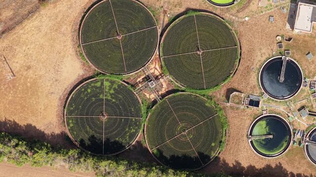 Top down aerial view of circular clarifiers and trickling filter beds at a wastewater treatment plant in St Neots, UK