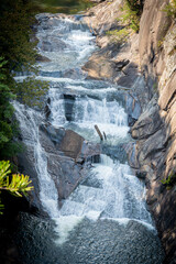 A closer view of powerful water rushing and cascading over massive rock formations, dropping into a deep pool at the bottom of a steep gorge. © CJWHiggins
