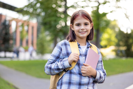 Young student girl smiling carrying backpack and book