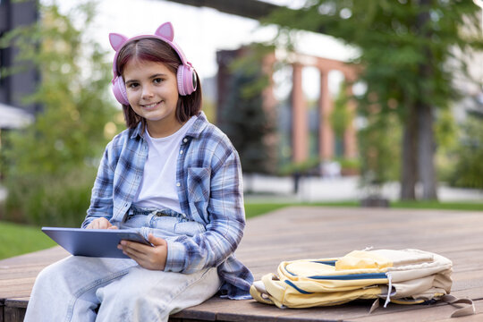 Girl student wearing headphones learning with tablet in park