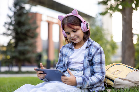 Young girl watching content on tablet with headphones in park