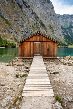 Wooden boathouse with walkway on shore of clear green mountain lake Germany