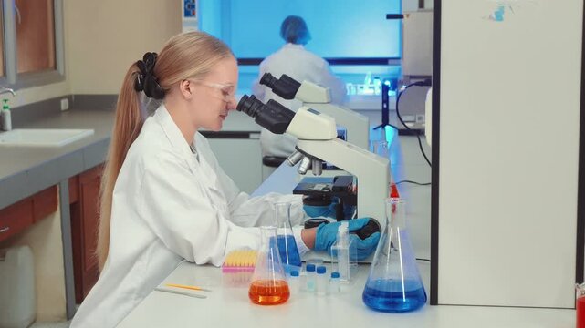 Scientist in a white lab coat using a microscope for research in a modern laboratory setting