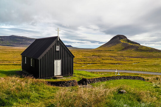 Panoramic landscape and black Krysuvik church. Krysuvikurkirkja is an old, wooden building with a white cross, door and windows. A typical building of Icelandic identity. Reykjanes Peninsula, Iceland.