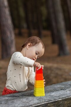 Toddler stacking colorful cups building tower outdoors