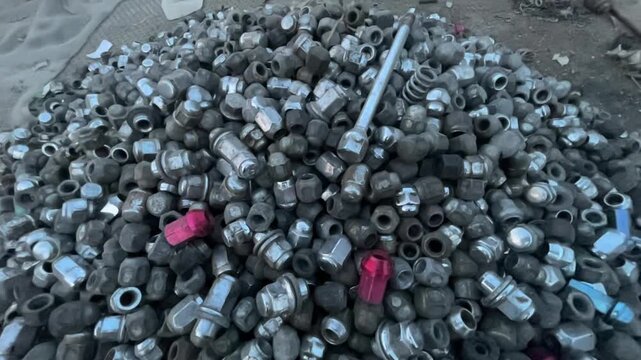 Pile of Used Automotive Wheel Lug Nuts at an Old Car Spare Parts Market, recycled car components, mechanical parts, and vintage auto repair culture.