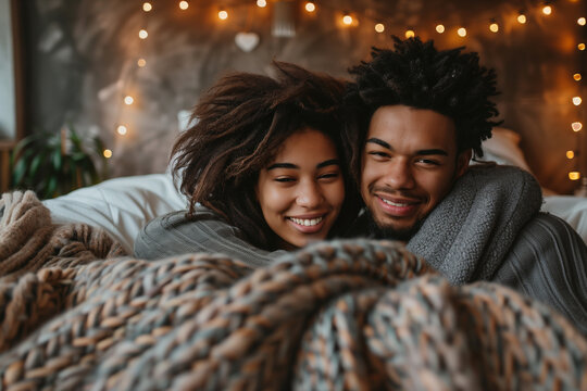 Romantic couple cuddling under a blanket at home