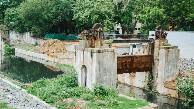 Rustic old manual dam with sluice gates and wheels over a stream heritage water infrastructure