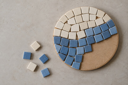 Mosa&iuml;que bleue et cr&egrave;me en cours de cr&eacute;ation sur un support rond