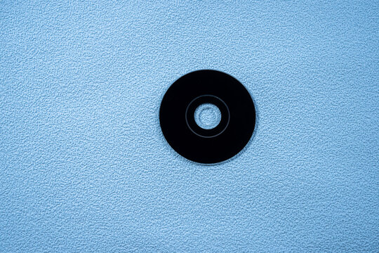 Black compact disc CD, on a blue background.