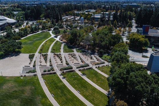 Aerial view shows the pedestrian paths, lawns, and corporate office buildings of a modern technology Googleplex campus on a sunny day in Mountain View, California.