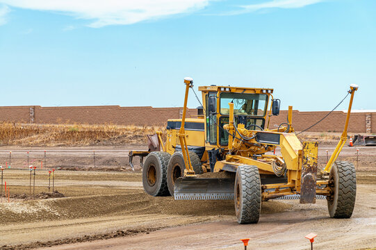 Powerful motor grader levels gravel for new road at construction site. Site preparation.
