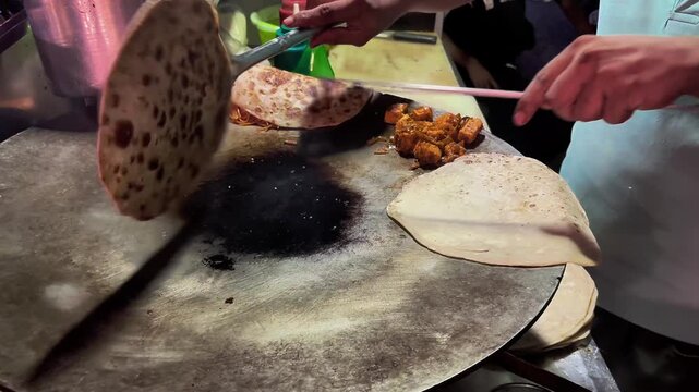 A street-food cooking scene showing ingredients being prepared on a large hot griddle, with eggs and other fresh components arranged for making a flavorful omelette in a traditional roadside setting.