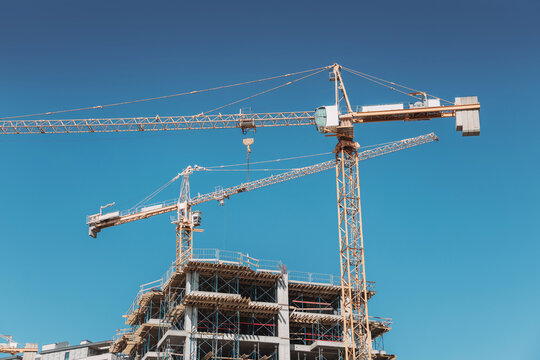Tower cranes constructing a new residential building, symbolizing growth, development, and progress in an urban landscape