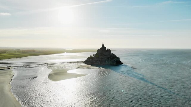 Island abbey of Mont Saint Michel in Normandy, France. Wide aerial footage of medieval landmark in backlight with exposed tidal flats