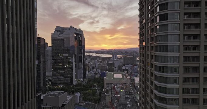 Osaka Japan Aerial v84 low reverse flyover between buildings in Ofukacho capturing downtown cityscape of Oyodonaka Kita Ward and Yodo river at sunset - Shot with 5k Camera - Oct 9th 2023
