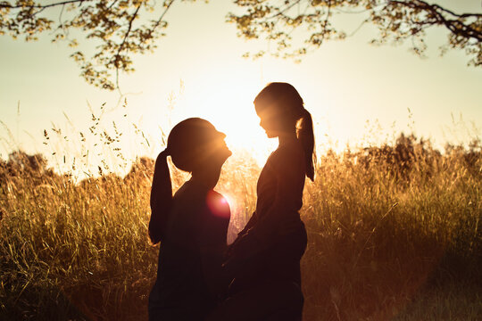 Mother holding daughter at sunset, family love, motherhood, parenting, childhood bonding and emotional connection concept
